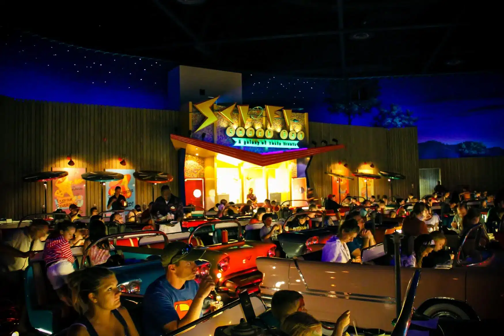 Sci Fi Dine-In Restaurant at Hollywood Studios - Guests sitting in classic cars eating food while watching a movie